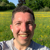 Jasha Joachimsthal staat in een veld met bloeiende boterbloemen. De zon schijnt op zijn gezicht.